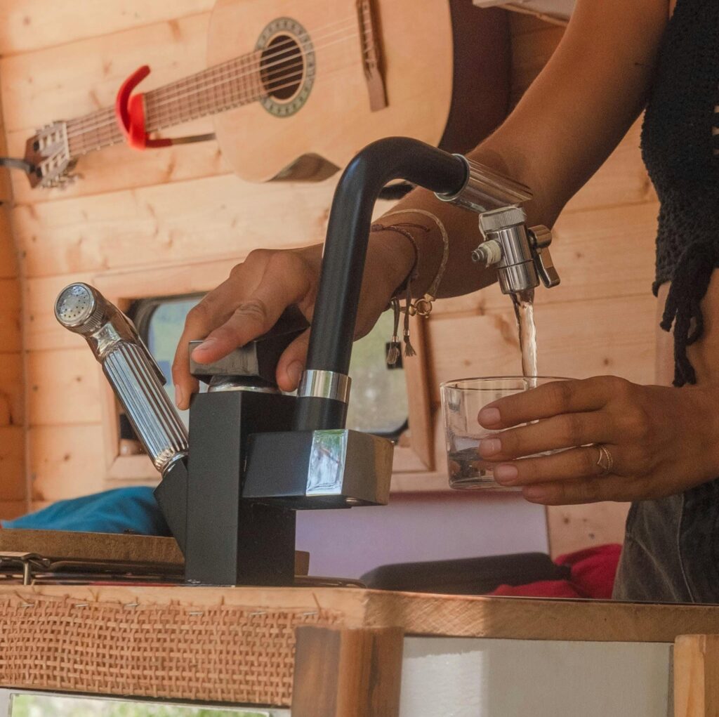 Gros plan sur un mitigeur avec de l'eau qui coule dans un van aménagé