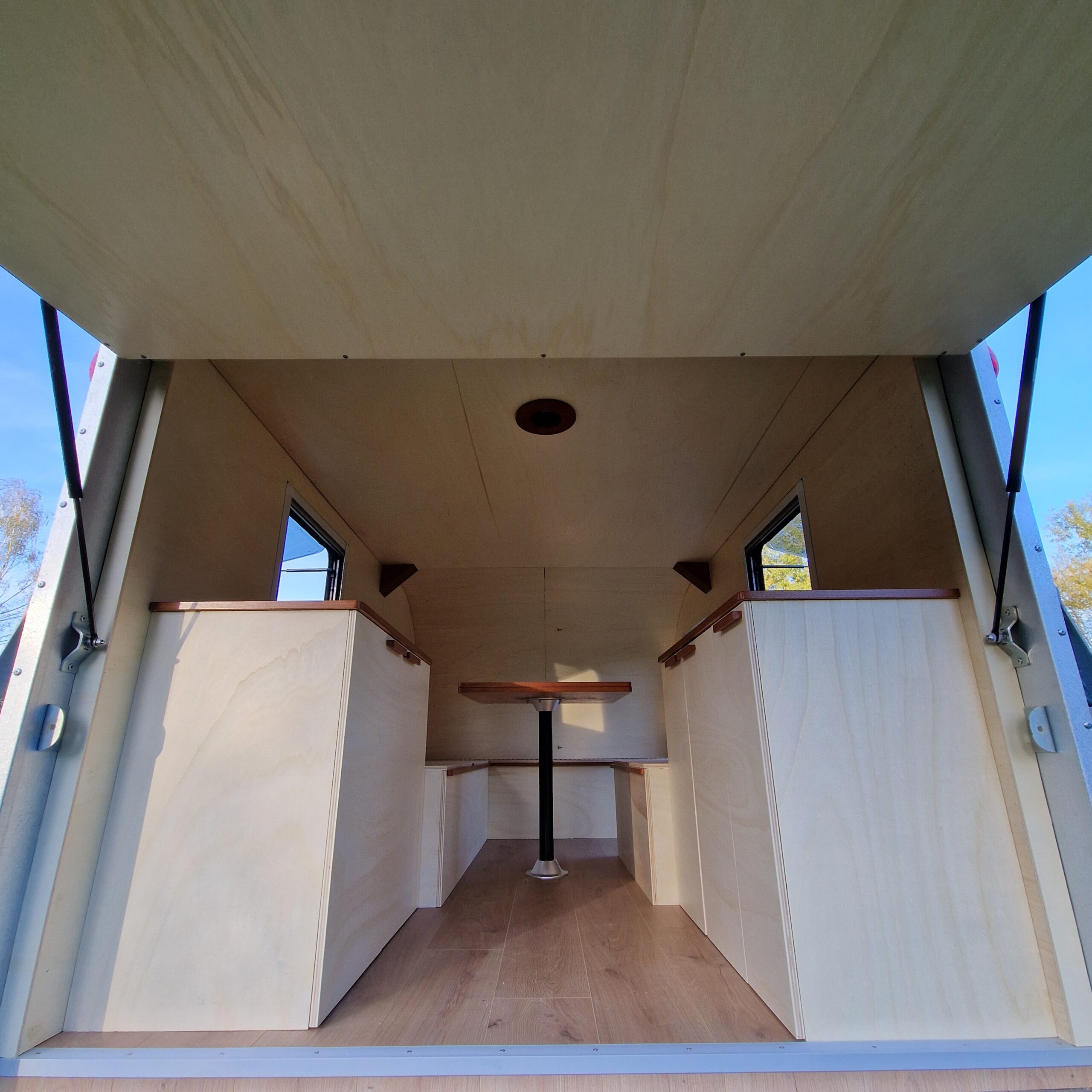 Intérieur d'une remorque aménagée à Bordeaux : harmonie entre les modules en peuplier vernis et les plans de travail en bois d'okoumé.