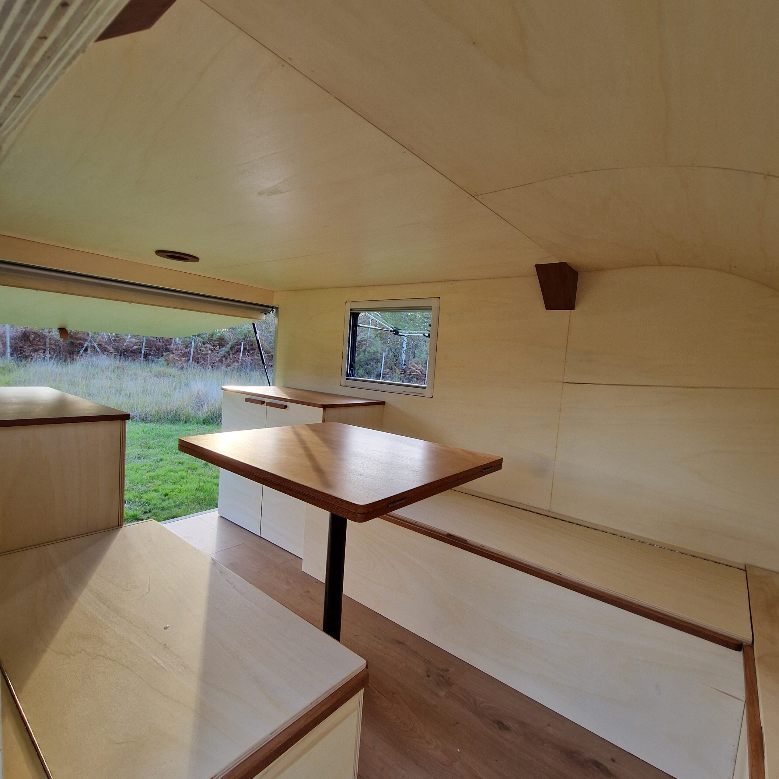 Vue d'ensemble de l'intérieur d'une remorque aménagée avec mobilier sur mesure et finitions bois haut de gamme à Bordeaux.