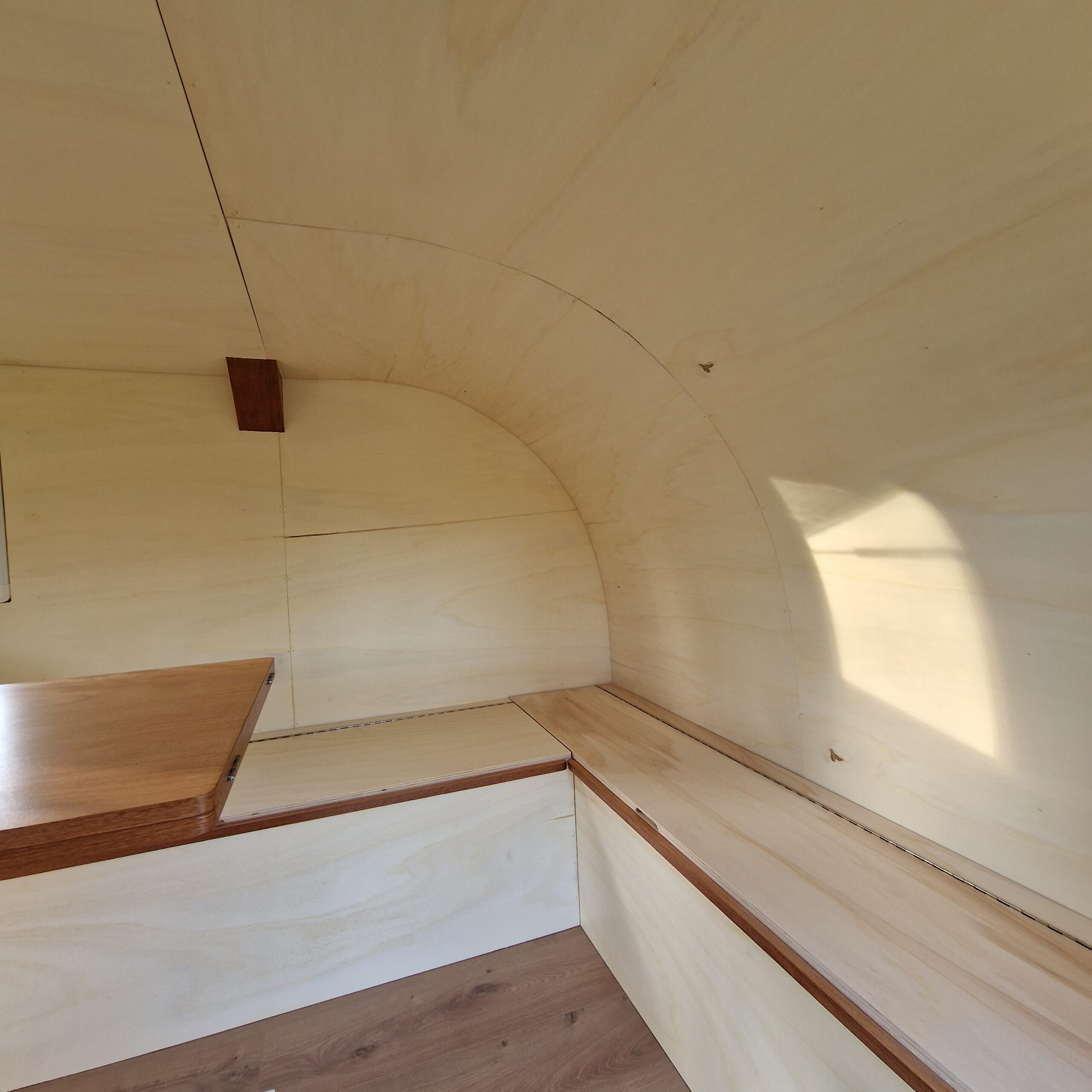 Focus sur l'habillage arrondi en bois du plafond d'une remorque aménagé avec des finitions courbes sur mesure à Bordeaux.