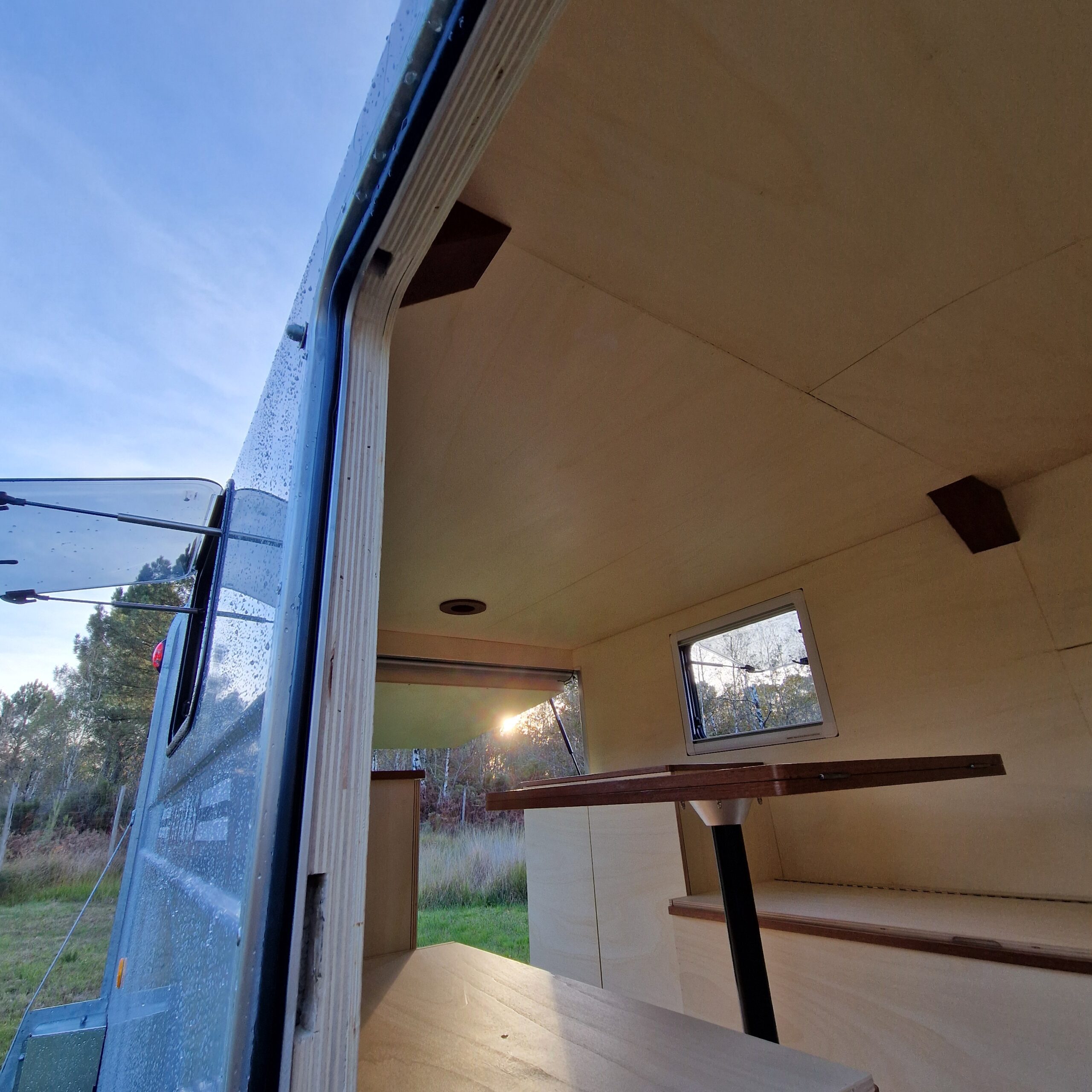 Zoom sur le cadre de finition arrondi en bois épousant la carrosserie d'une porte latérale de remorque aménagée à Bordeaux.